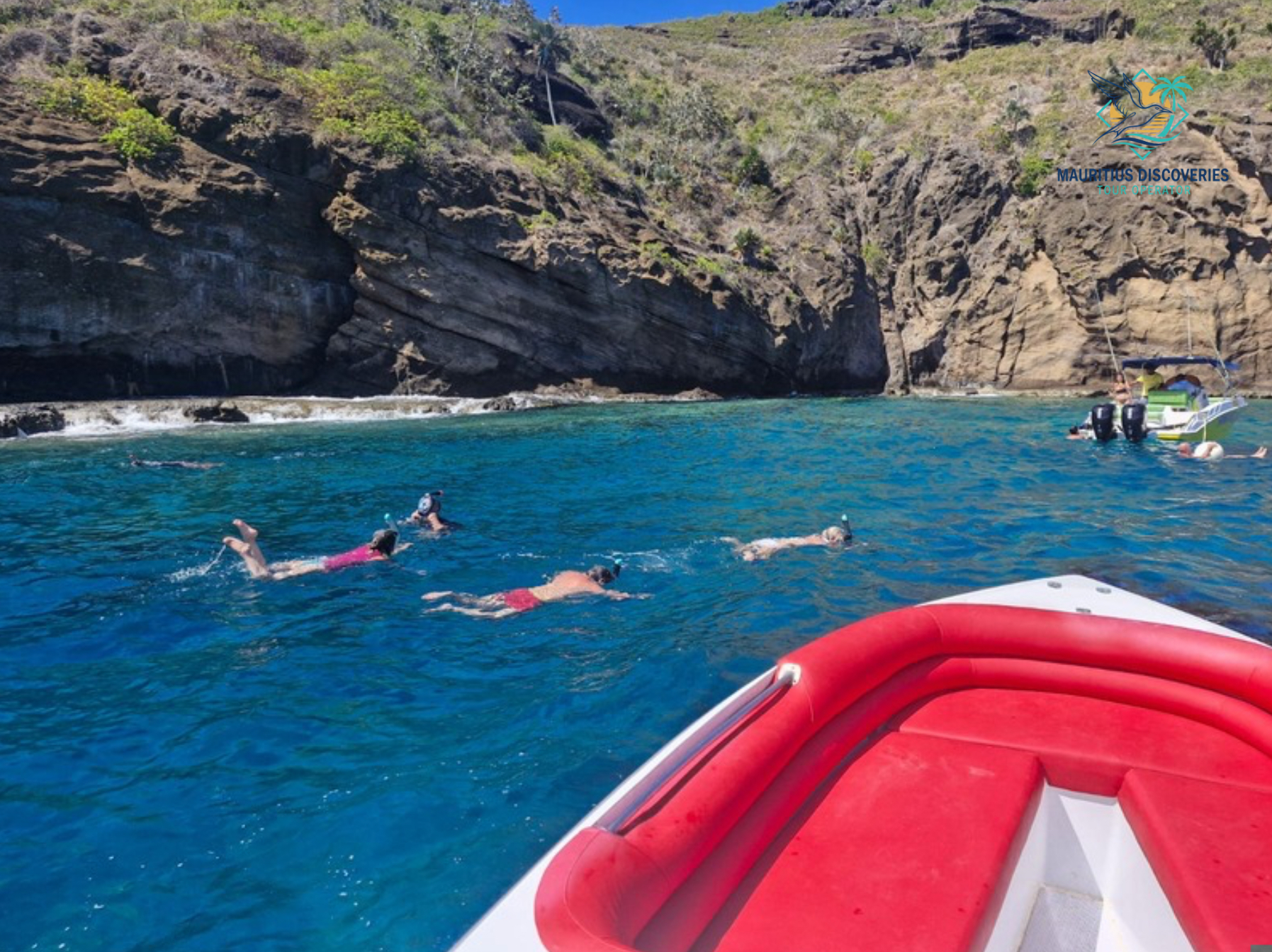 Snorkellers beside a rocky island on a north Mauritius boat trip