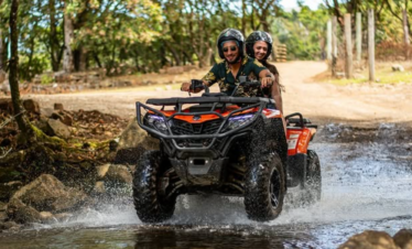 Visitors riding a quad bike through shallow water at Valle Adventure Park in Mauritius