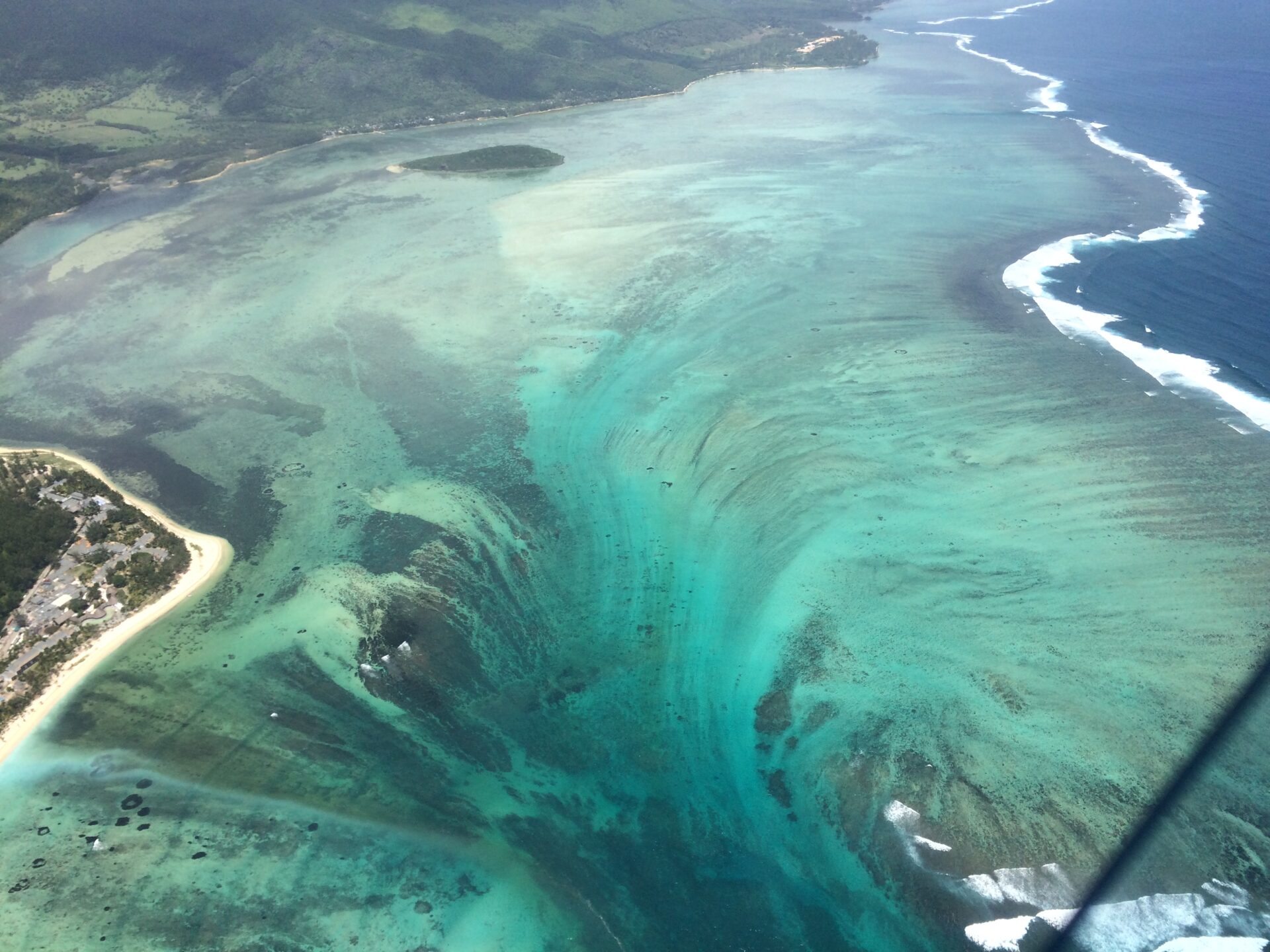The underwater waterfall illusion and turquoise lagoon seen from above near Le Morne