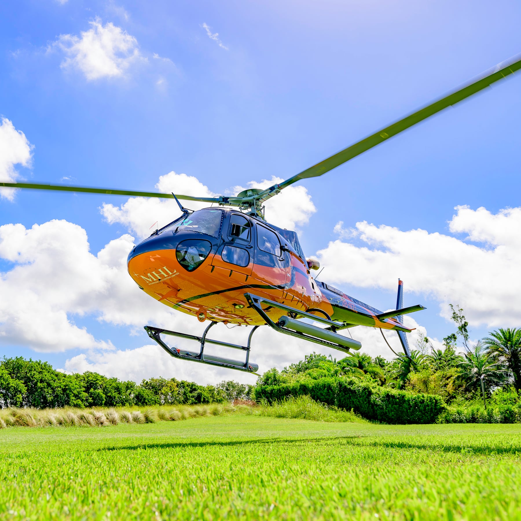 Orange and blue Mauritius Helicopter Limited helicopter above a helipad